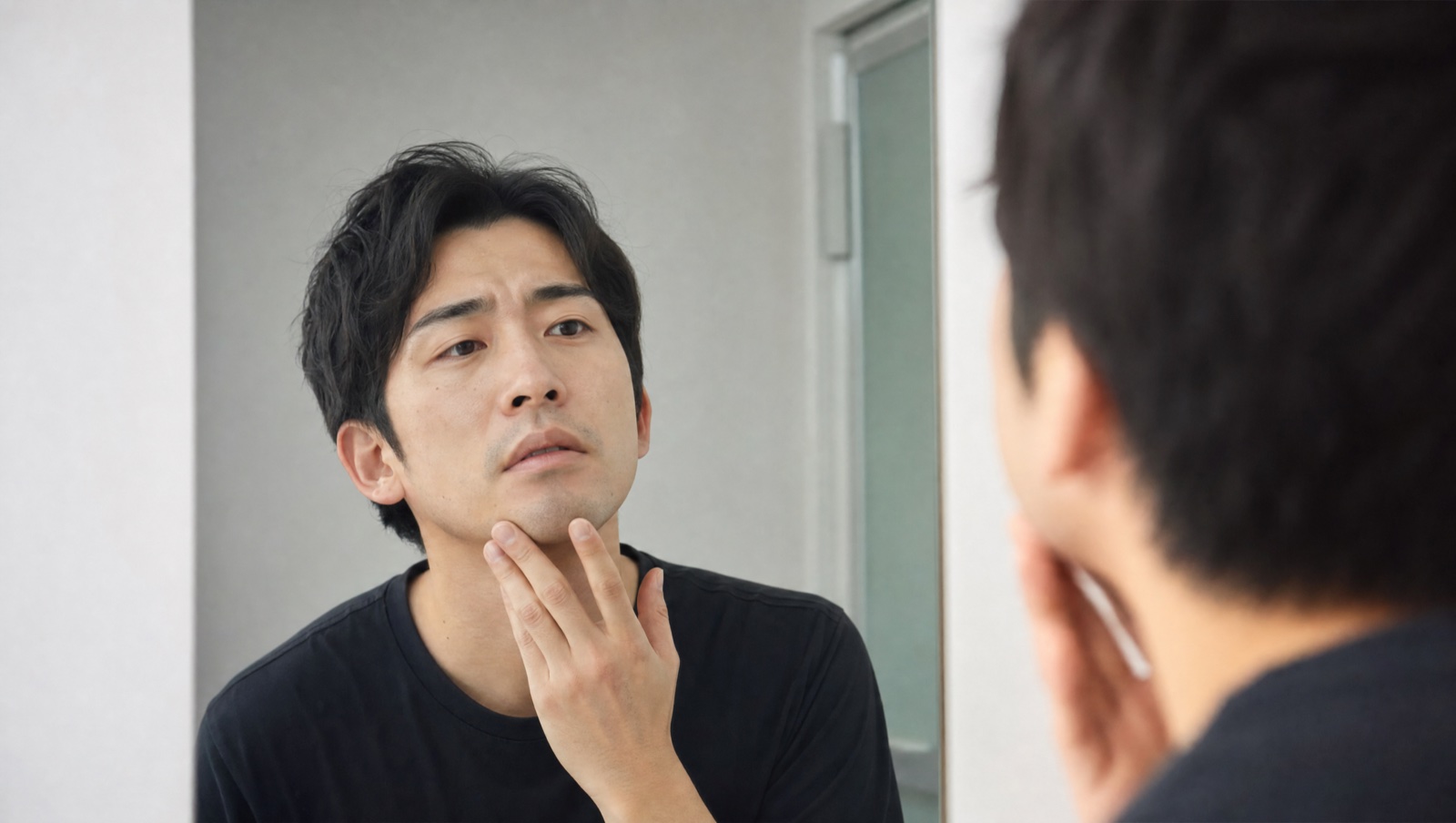 鏡でヒゲの状態を確認する男性